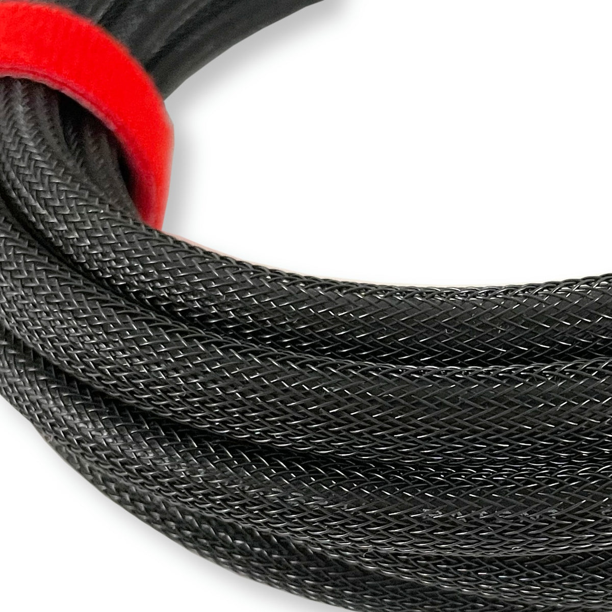 Close-up of a coiled black braided cable with a bright red loop or tie holding it together, photographed on a plain white background.